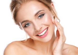 Beautiful woman smiles, touching her glowing skin lightly on the cheek