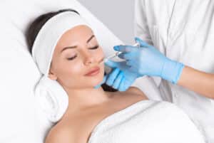Doctor's gloved hand administers Juvederm® in a smiling woman's wrinkles