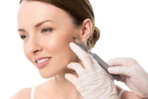Woman looks to the side and smiles during a dermaplaning treatment